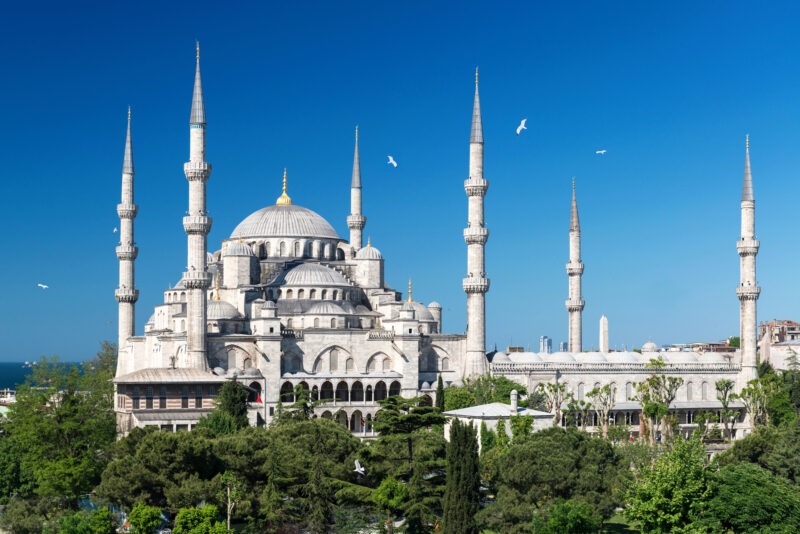 Uitgezoomde foto van de Blauwe Moskee in Istanbul tegen een strakblauwe lucht.