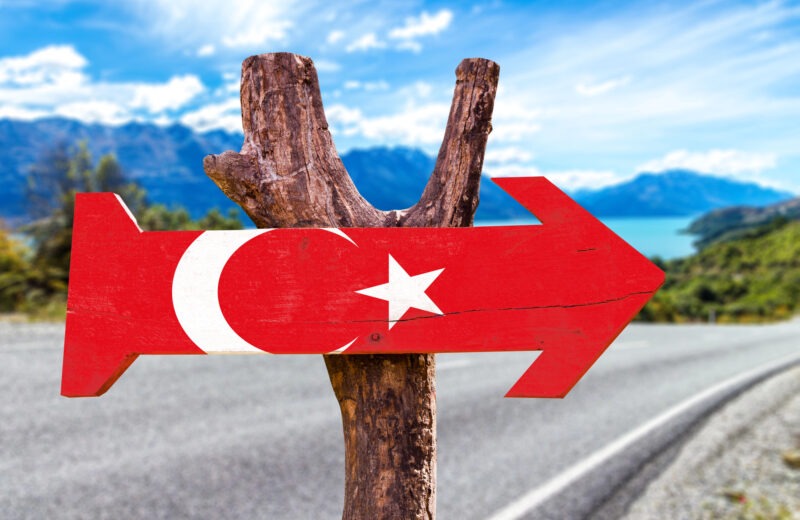 Een houten, pijlvormig bordje met de kleuren en kenmerken van de Turkse vlag.